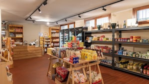 A grocery store interior with shelves stocked with various products, a wooden counter, and a display of bottled beverages. - Resort Palace Sestriere 1 E 2 (Sestriere)