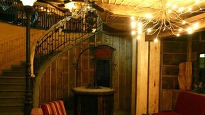 Een gezellige kamer met een houten trap, een rode bank en een gestreept voetenbankje.