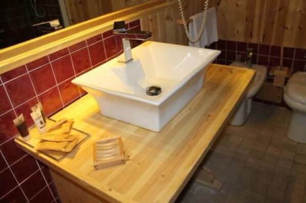 A bathroom with a white sink, wooden countertop, and red-tiled walls. - Grand Hotel Sestriere (Sestriere)