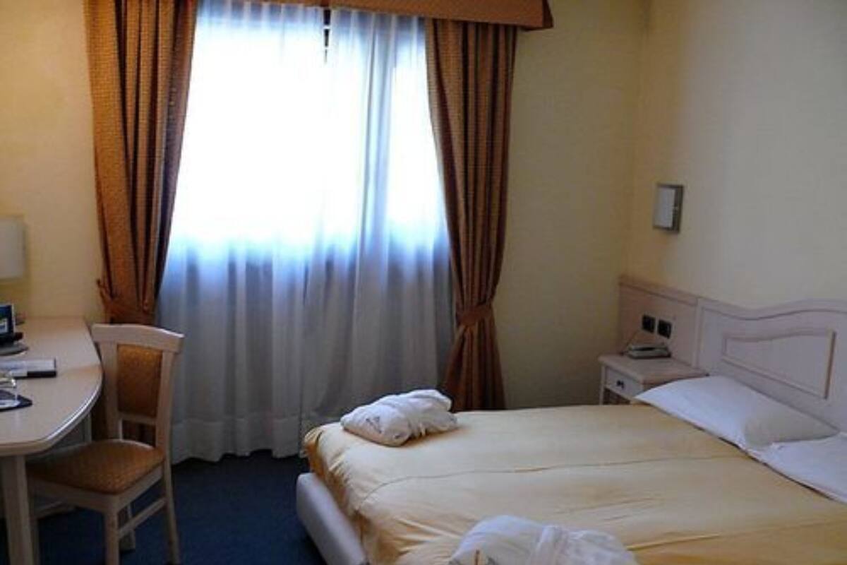 A hotel room with a bed, a desk, a chair, and a nightstand.