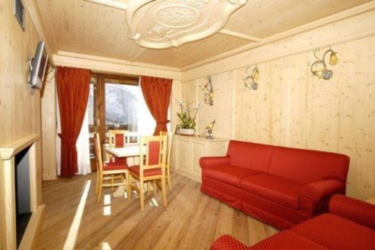 A cozy room with a red sofa, wooden flooring, a dining area with a table and chairs, and a fireplace.