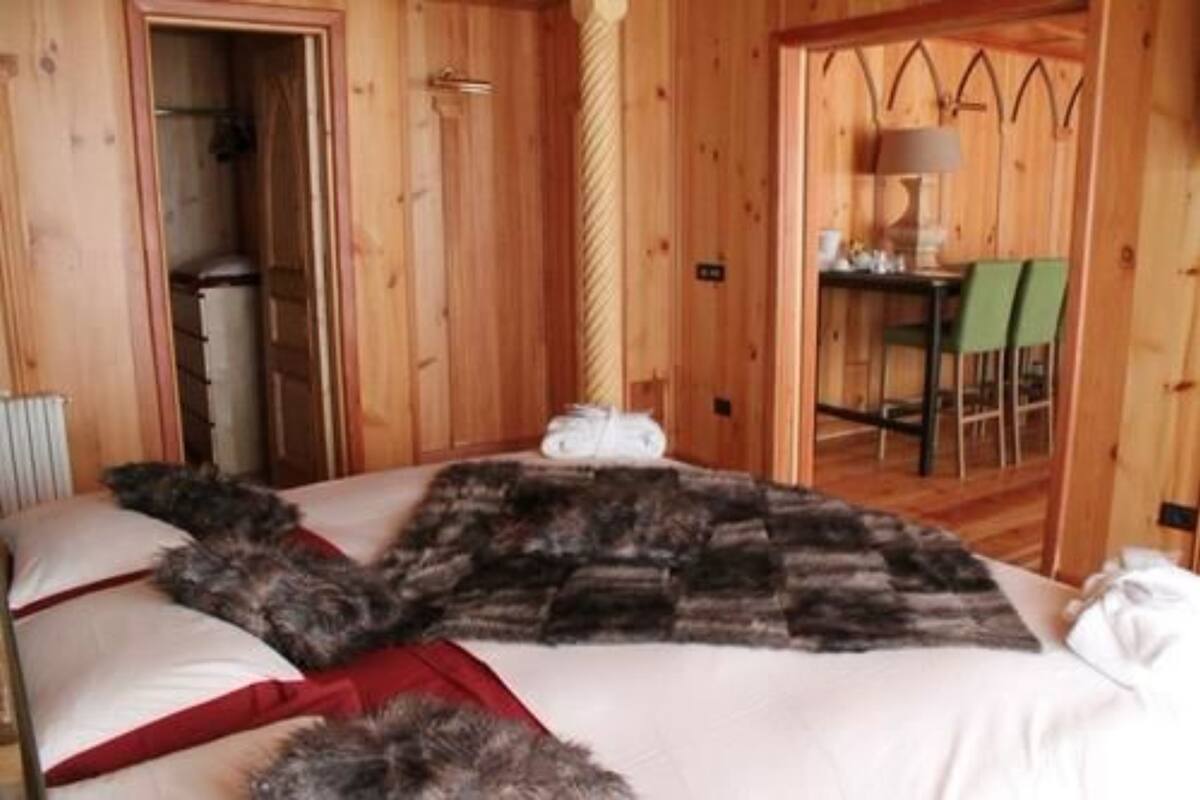 A wooden room with a bed, a table with chairs, and a door leading to a bathroom.