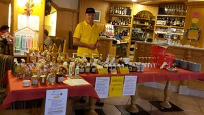 A bar with a wooden interior, shelves stocked with bottles, and a table displaying various bottles and glasses. - Hotel Bonapace (Pinzolo)