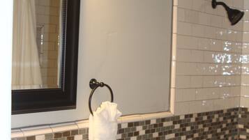 A bathroom with a sink, mirror, shower, and a decorative dog statue.