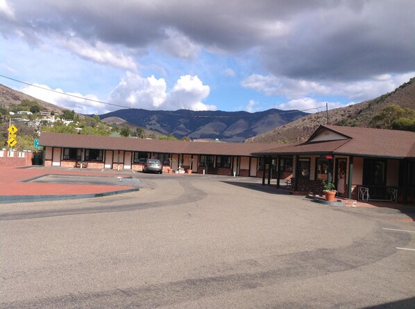 A motel with a central parking area and multiple rooms with large windows.