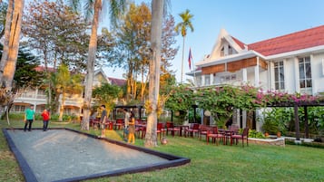 Relax in our serene outdoor space, surrounded by lush greenery and palm trees, with a croquet field and comfortable seating areas.
