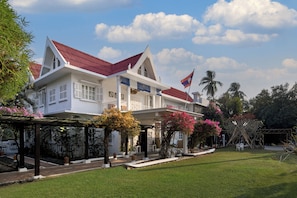 A white building with a red roof, surrounded by greenery and a clear sky. - Homm Souvannaphoum Luang Prabang, part of Banyan Group (Luang Prabang)