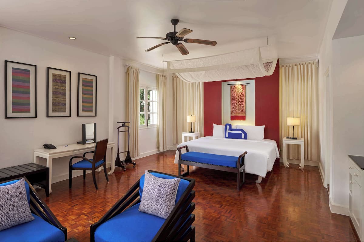 Une chambre d’hôtel équipée d’un lit, d’un bureau, d’une chaise et d’un ventilateur de plafond.