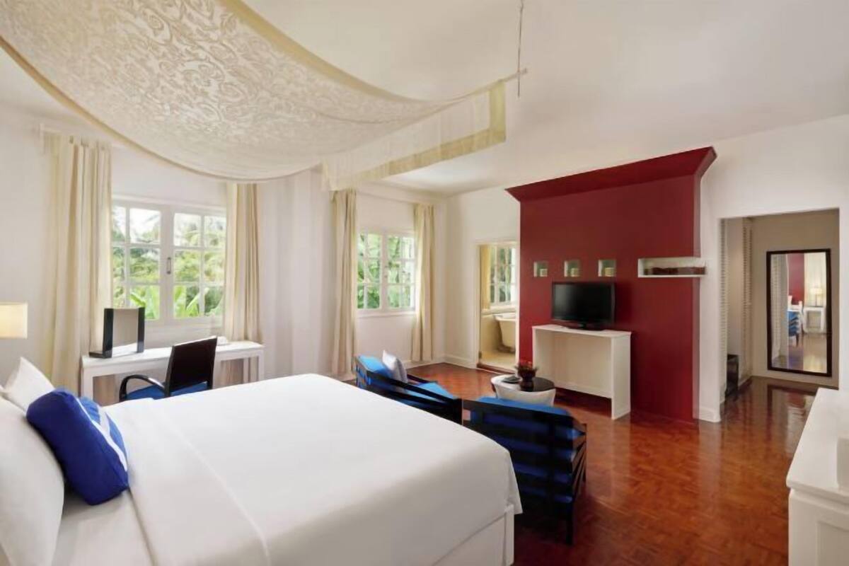 Une chambre d’hôtel avec un lit, un bureau, une télévision et une vue sur la verdure.
