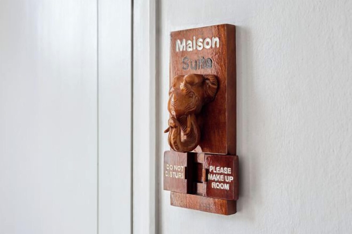 Une enseigne en bois à fixer au mur, ornée d’une tête de lion, avec l’inscription « Maison Soleil » et les indications « Ne pas déranger » et « Veuillez préparer la chambre ».