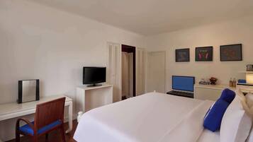 A hotel room with a bed, a desk with a chair, a television, and a laptop.