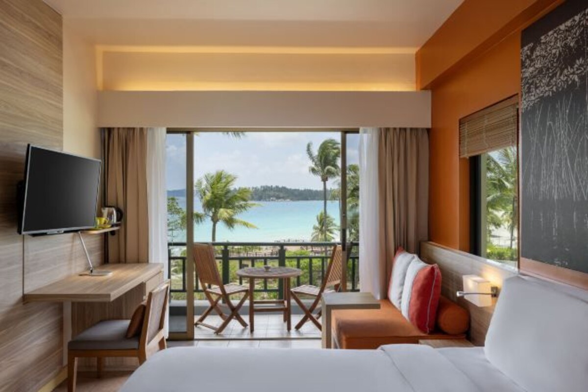 A hotel room with a balcony, a bed, a TV, a desk, and a table with chairs.
