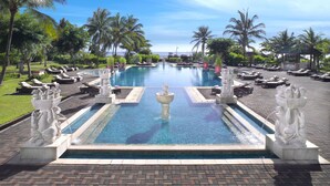 A large pool with statues, sun loungers, and palm trees. - Homm Laguna Bintan (Bintan)