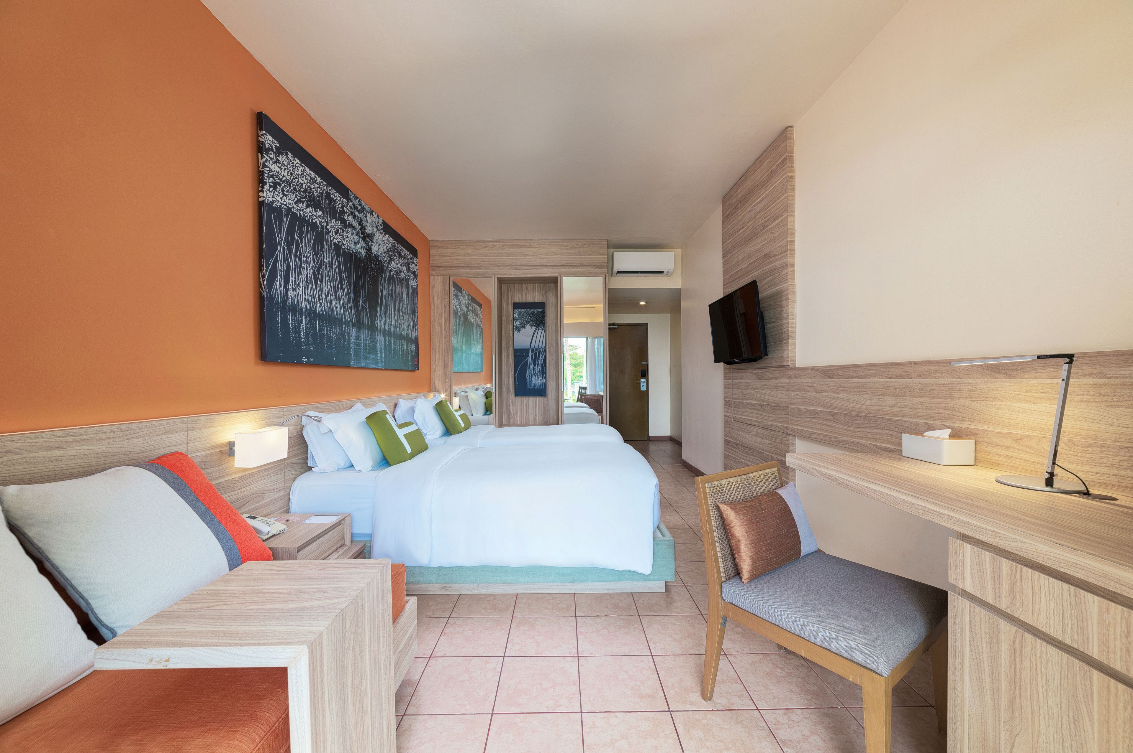 A hotel room with a large bed, a desk, a chair, and a TV.