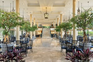 A spacious indoor area with multiple seating arrangements, a central staircase, and large windows allowing natural light. - Homm Laguna Bintan (Bintan)