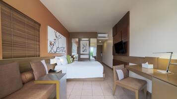 A hotel room with a bed, a desk, a chair, a TV, and artwork on the walls.