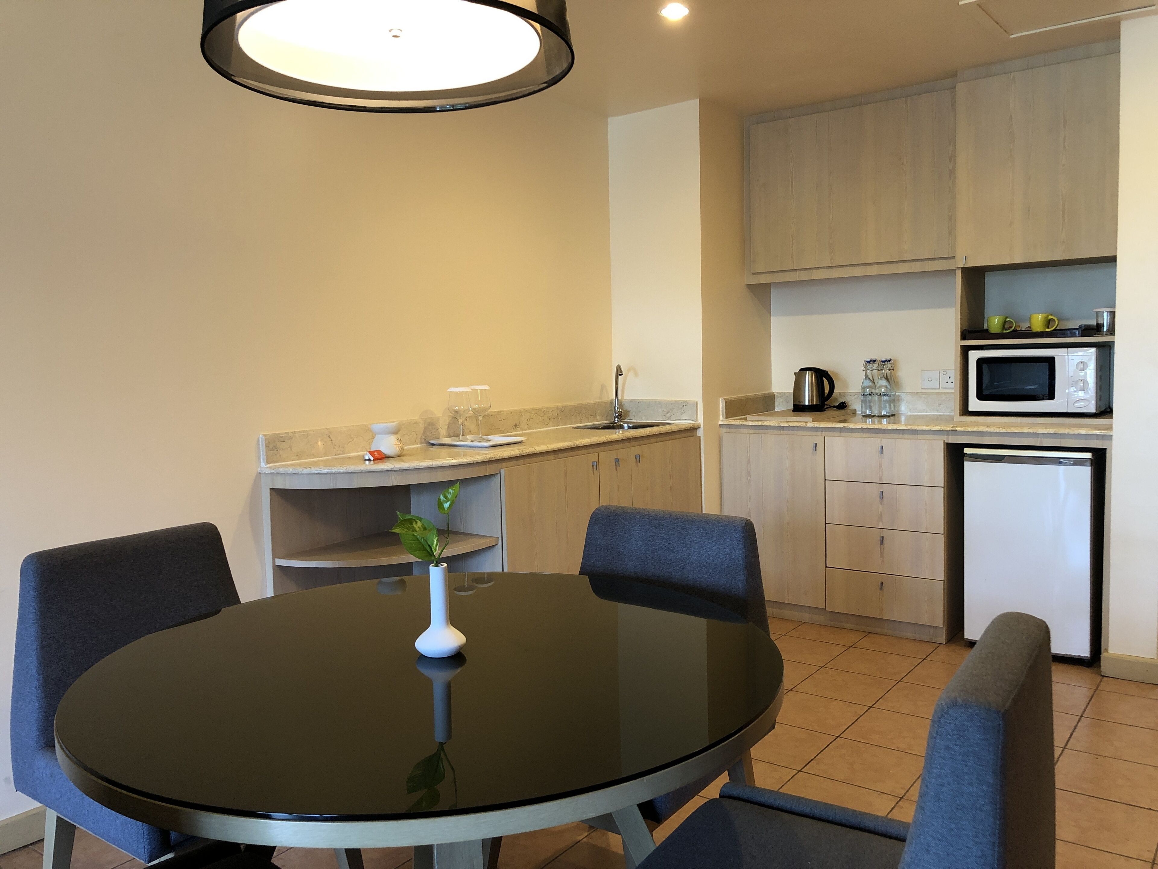 A modern kitchen with a round dining table, chairs, a small plant, and built-in appliances.