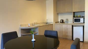 A modern kitchen with a round dining table, chairs, a small plant, and built-in appliances.
