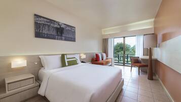 A hotel room with a large bed, a nightstand, a desk, a chair, a balcony with a view, and a painting on the wall.