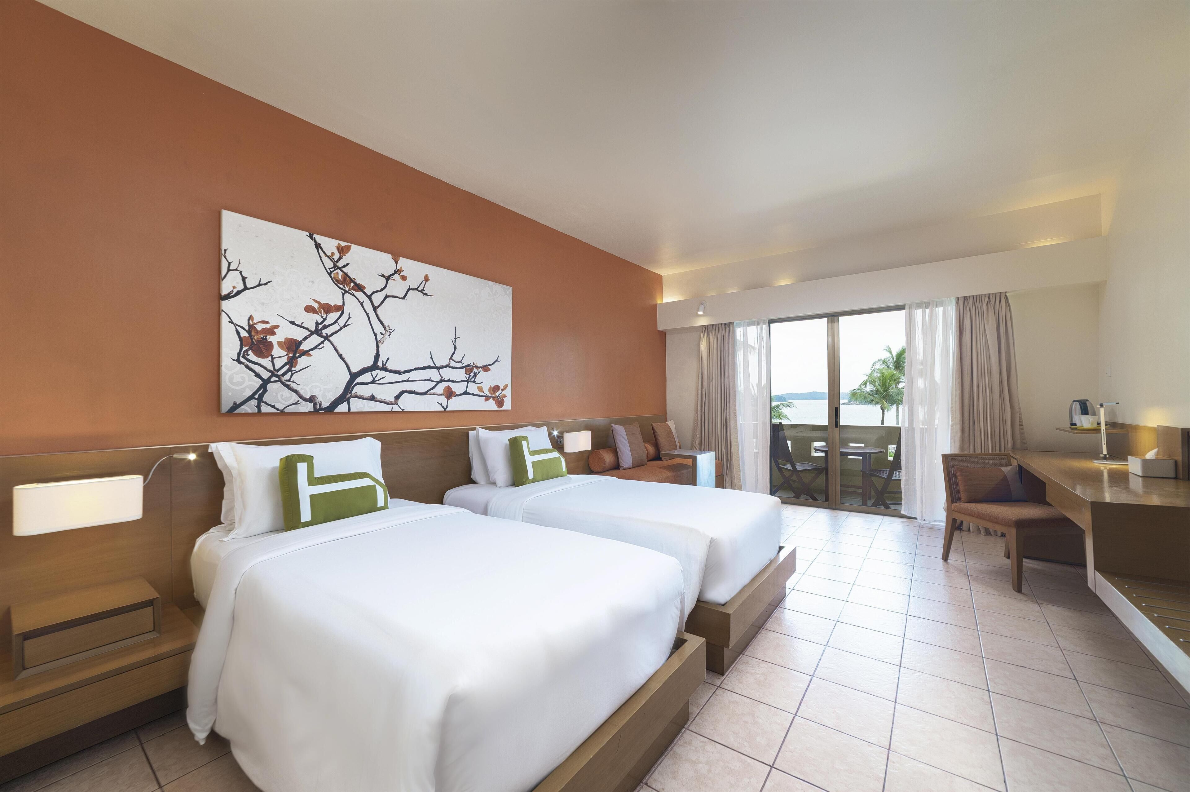 A hotel room with two beds, a desk, and a view of the outdoors.