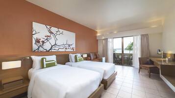 A hotel room with two beds, a desk, and a view of the outdoors.