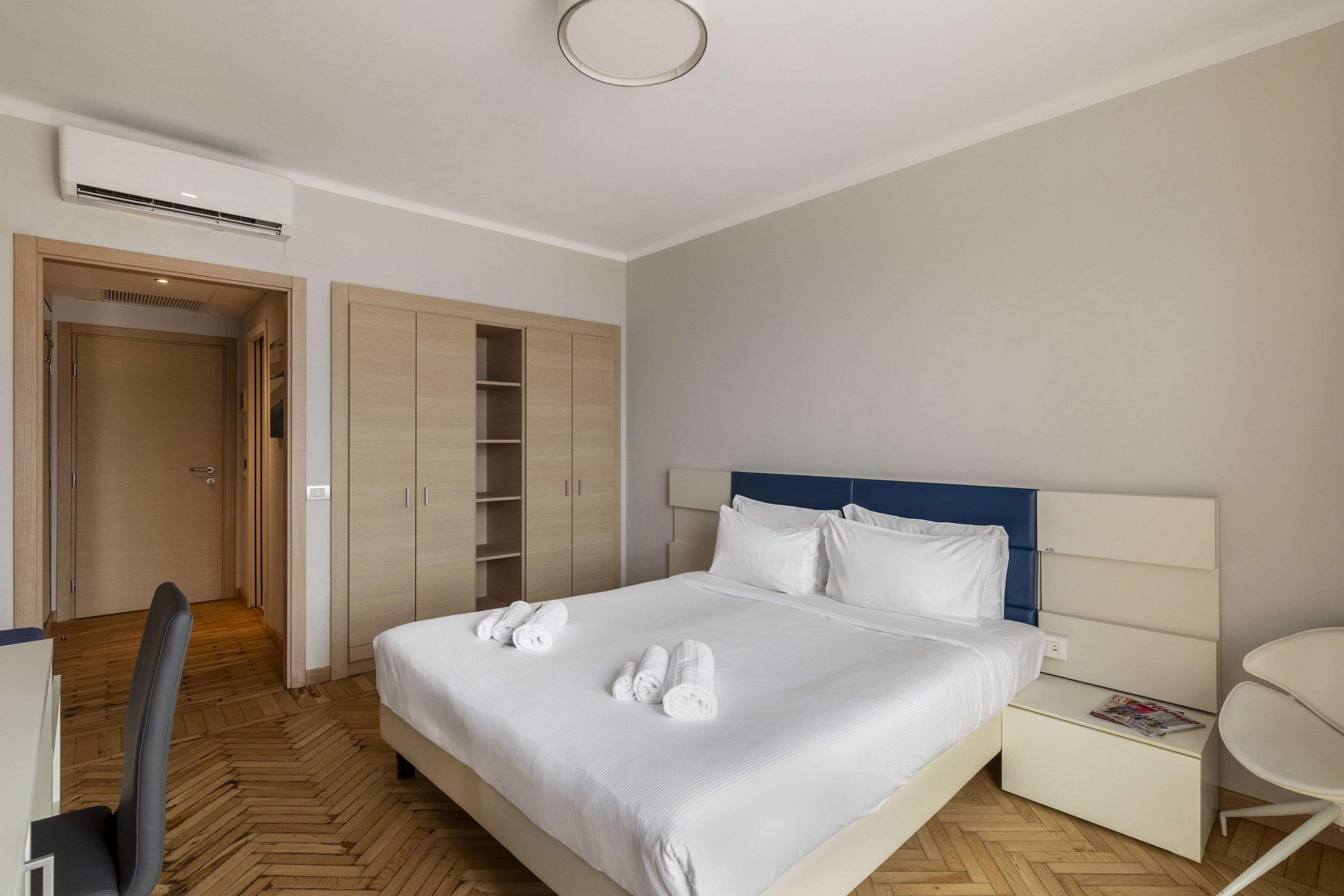 Ein Hotelzimmer mit Bett, Schreibtisch, Stuhl, Kleiderschrank und Nachttisch.
