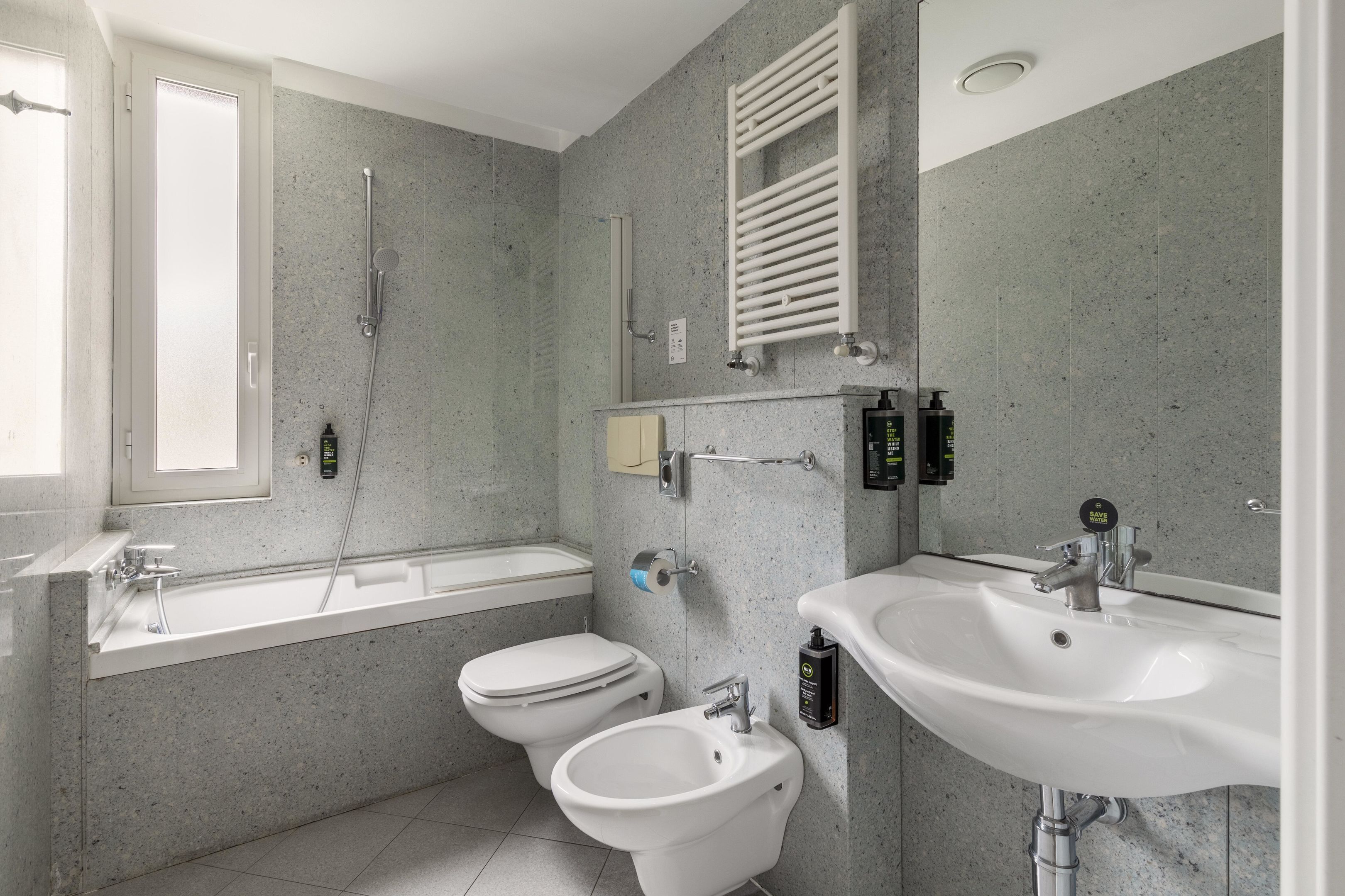 Een moderne badkamer met een bad, toilet, douchetoilet en wastafel.