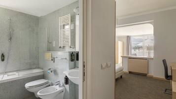 Un baño moderno con una bañera, dos inodoros, un bidé y un lavamanos.