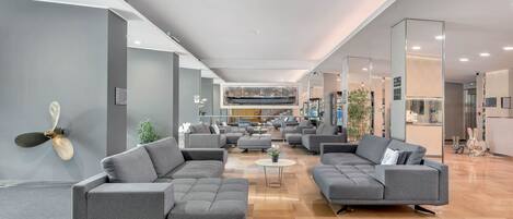 A spacious lobby with modern grey sofas, a coffee table, and a decorative fan.