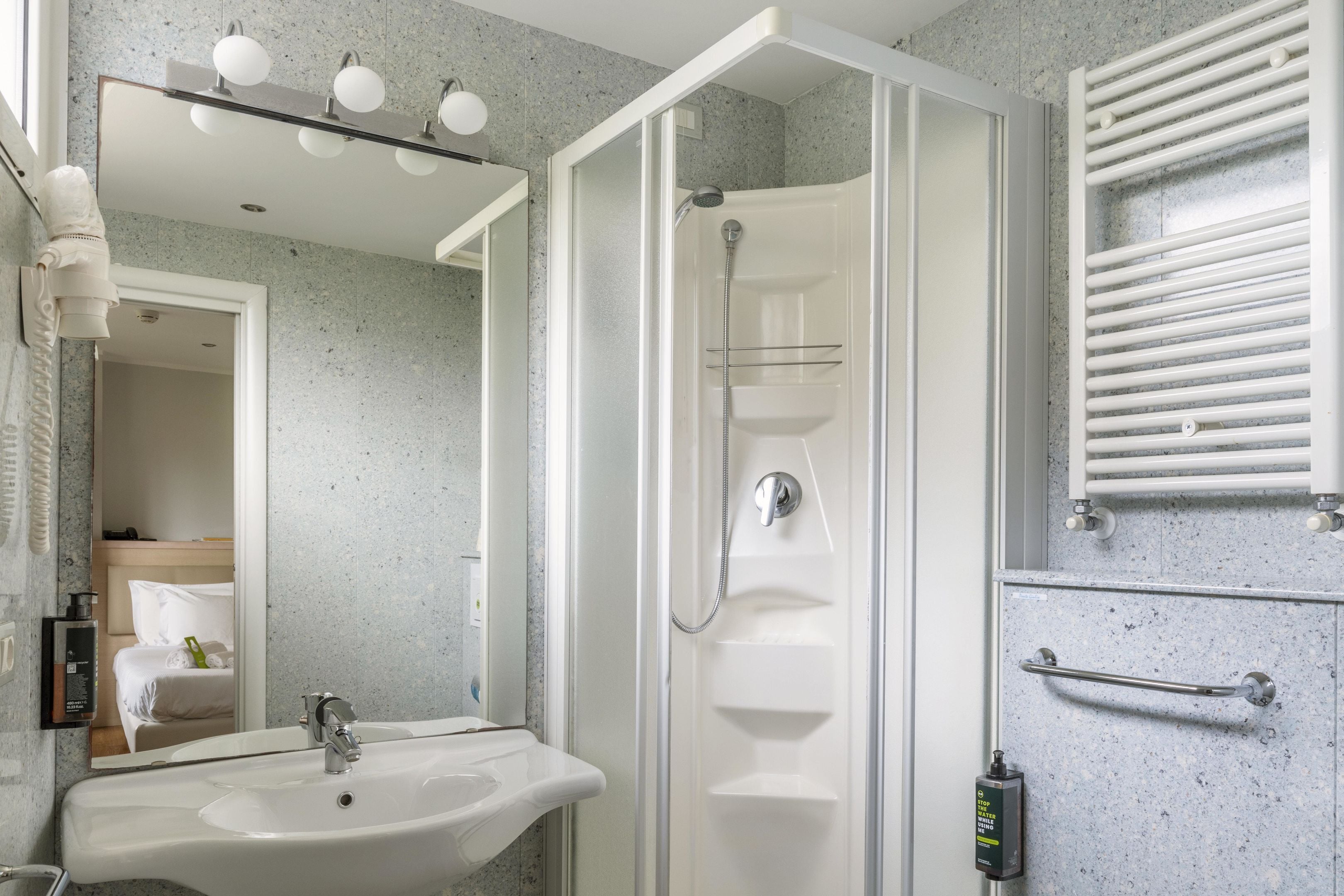 A modern bathroom with a glass-enclosed shower, a sink with a mirror above it, and a towel rack.