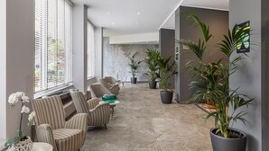A spacious indoor area with striped chairs, a stone floor, and potted plants. - B&B Hotels Park Hotel Suisse Santa Margherita Ligure (Santa Margherita Ligure)