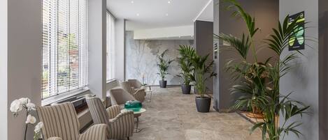 A spacious indoor area with striped chairs, a stone floor, and potted plants.