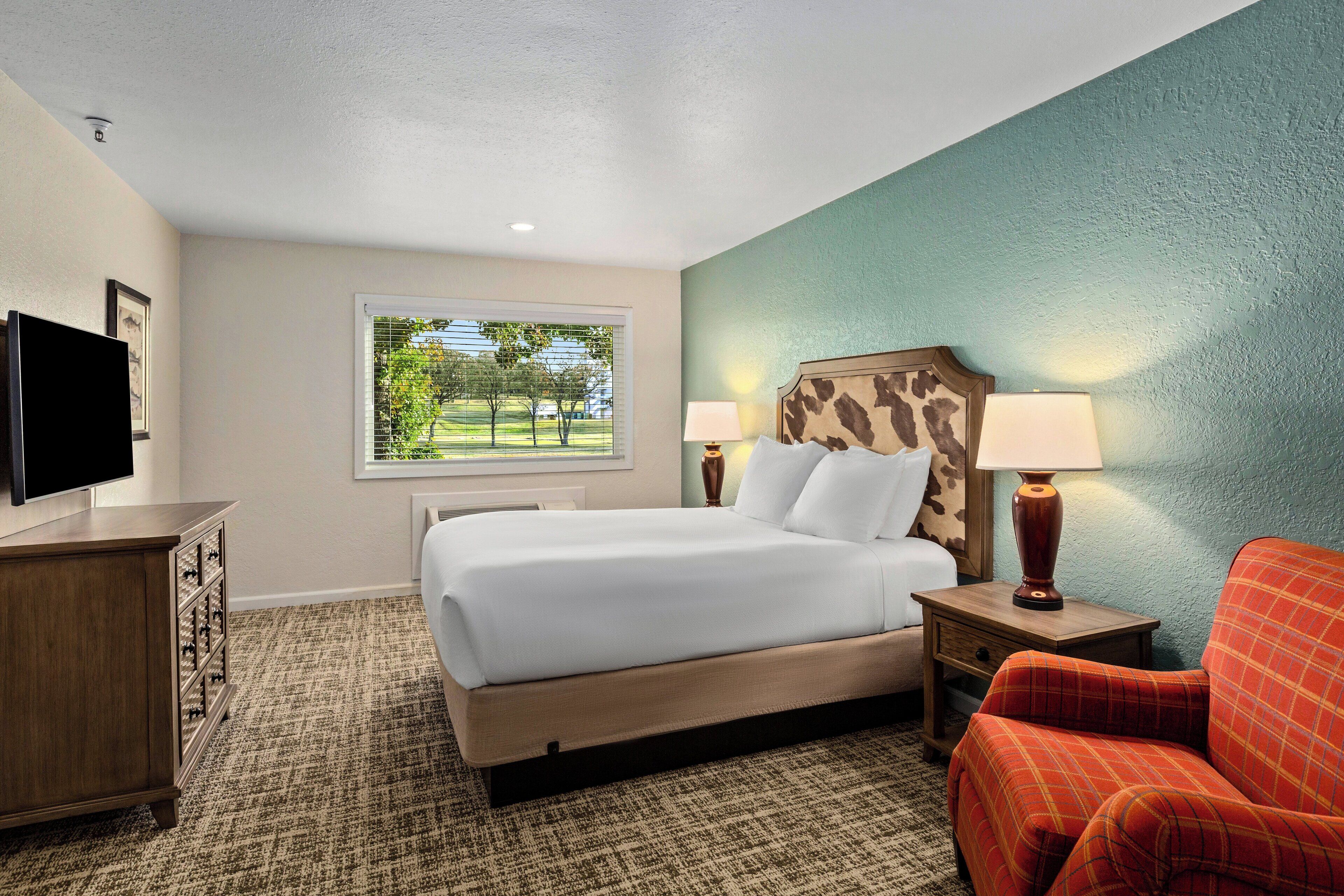 A hotel room with a bed, a TV, a desk, and a chair.