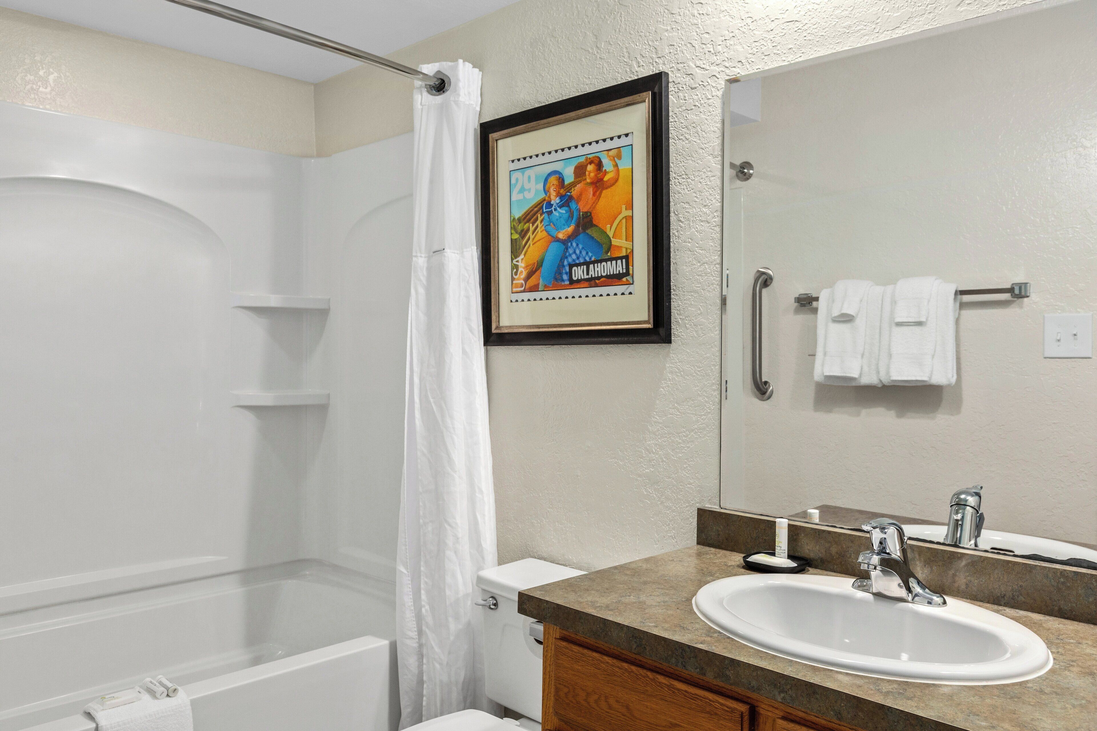 A bathroom with a bathtub, a sink, a mirror, and a shower curtain.