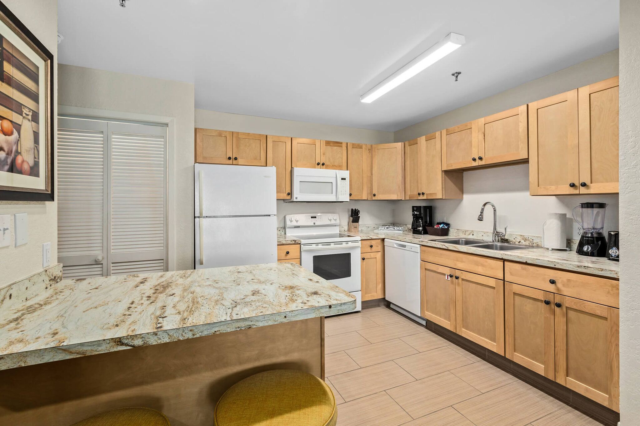 A kitchen with wooden cabinets, a white refrigerator, a microwave, a stove, and a sink.