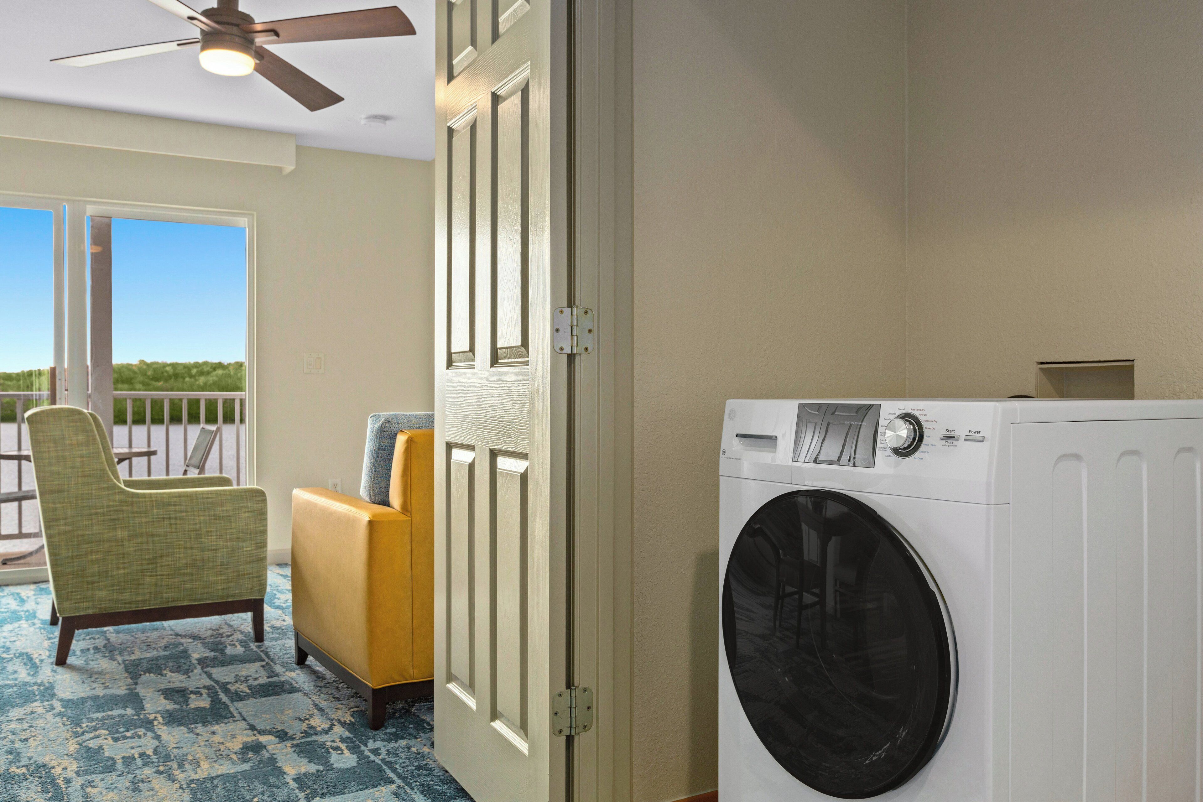 A laundry room with a washing machine, a door, and a chair.