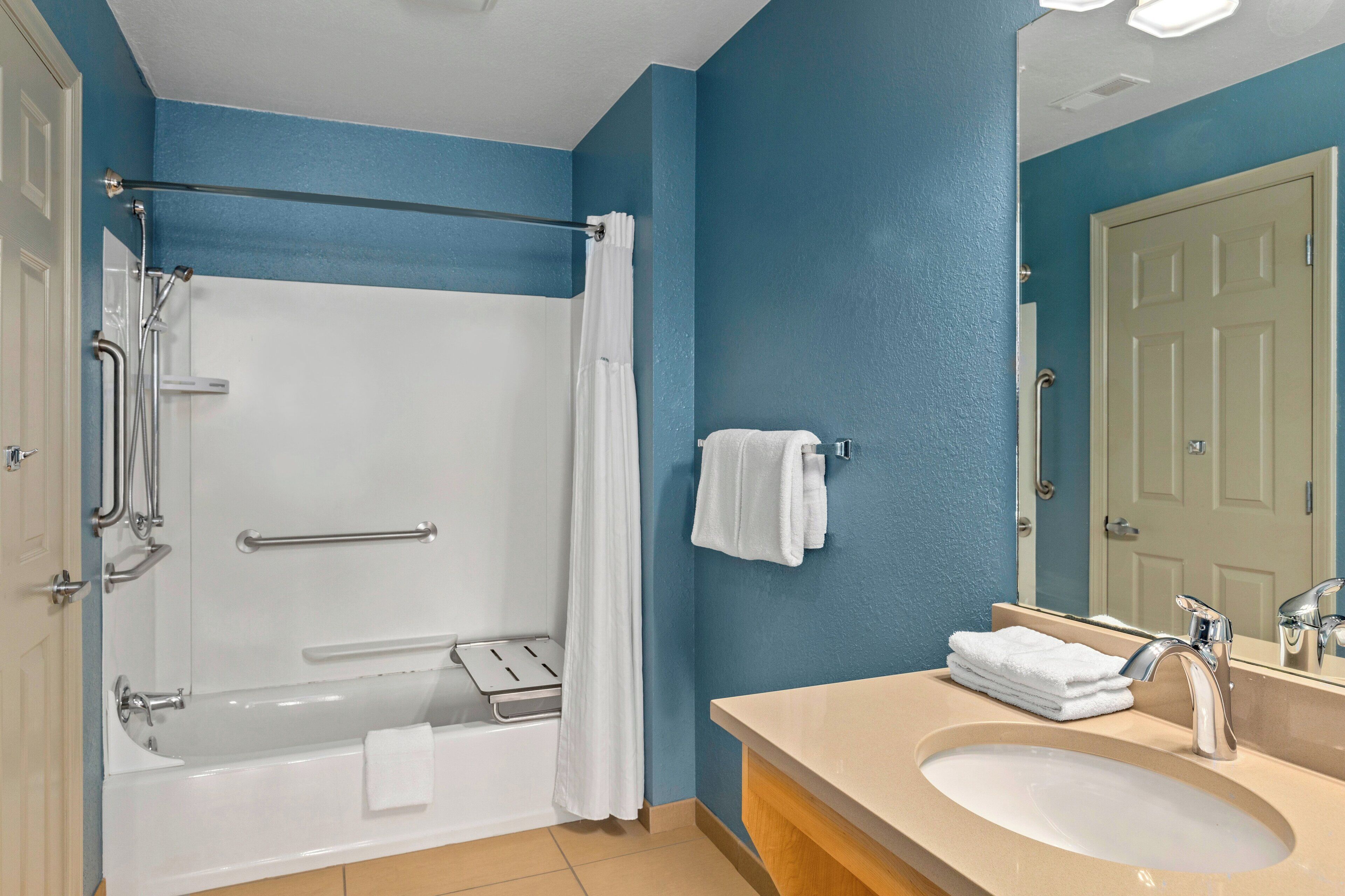 Een badkamer met een bad, douche, wastafel en spiegel.
