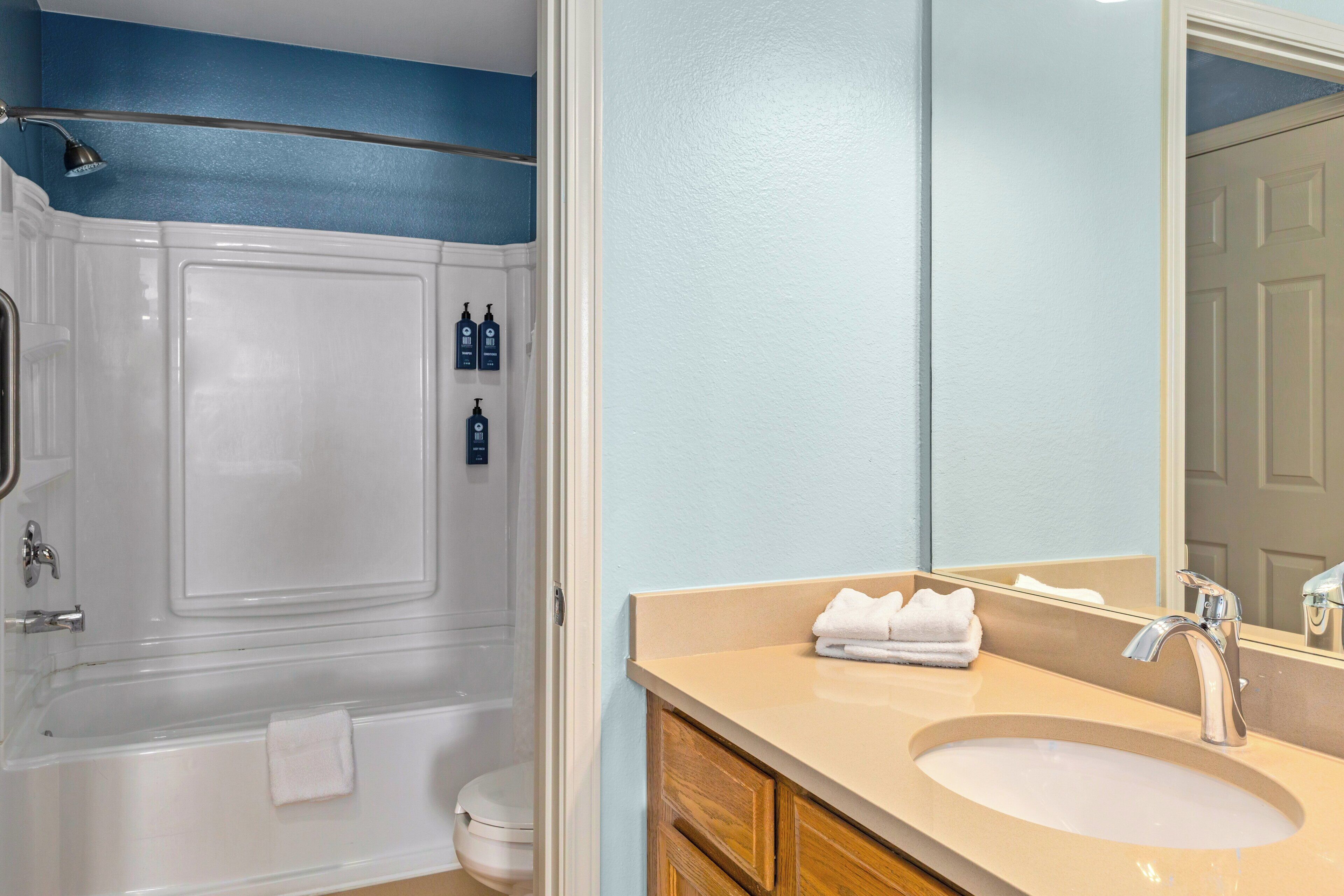 A bathroom with a bathtub, a sink, and a mirror.