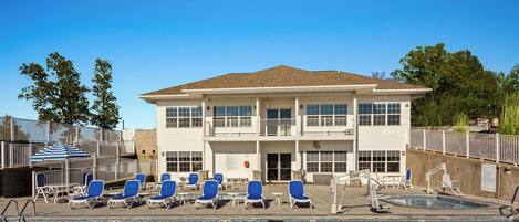 A swimming pool with blue chairs and a building with a balcony in the background.
