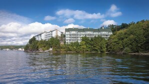 A multi-story hotel with balconies, situated by a body of water, surrounded by trees. - WorldMark Lake of the Ozarks (Osage Beach)