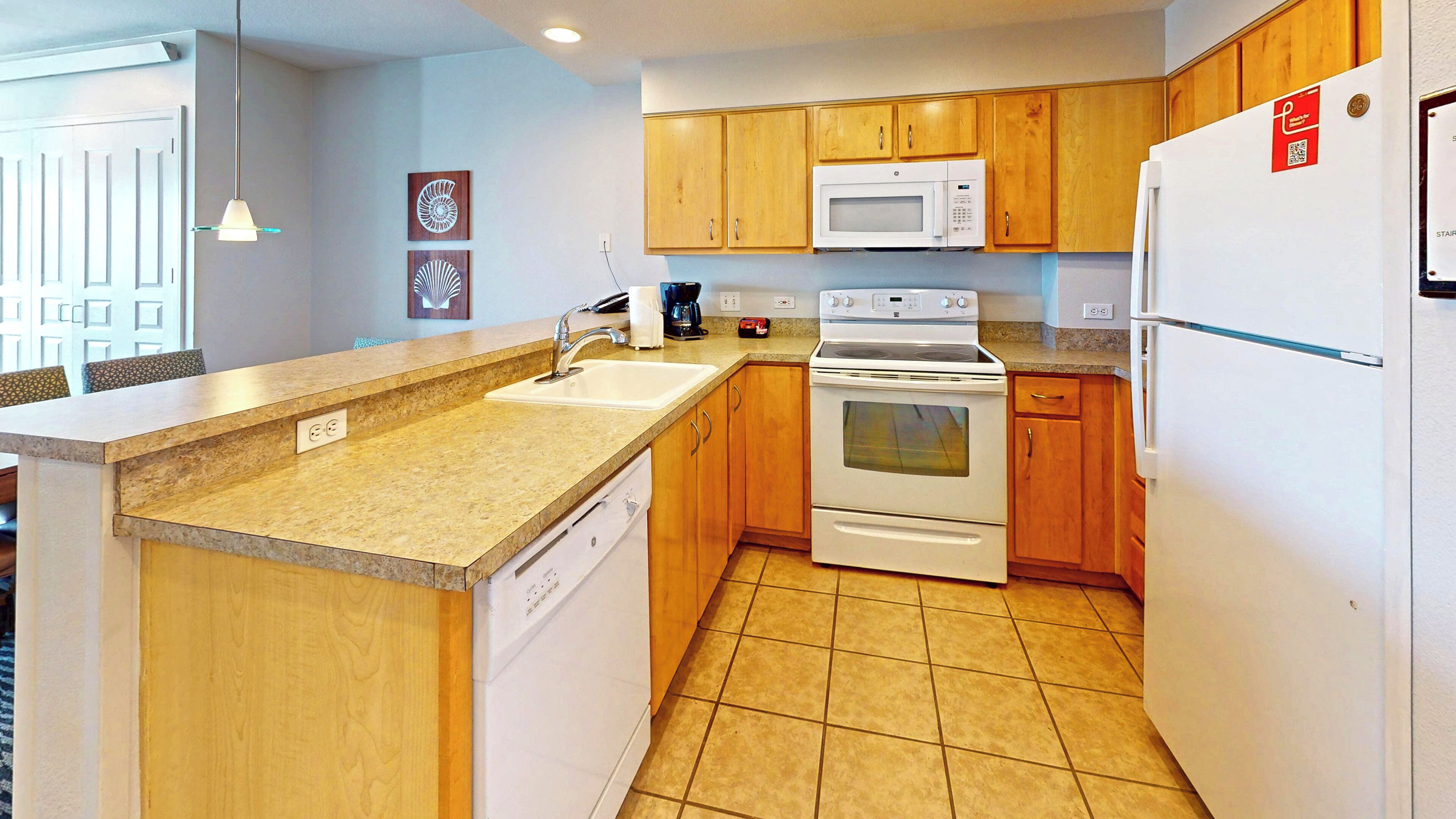A compact kitchen with wooden cabinets, a built-in microwave, an oven, and a refrigerator.