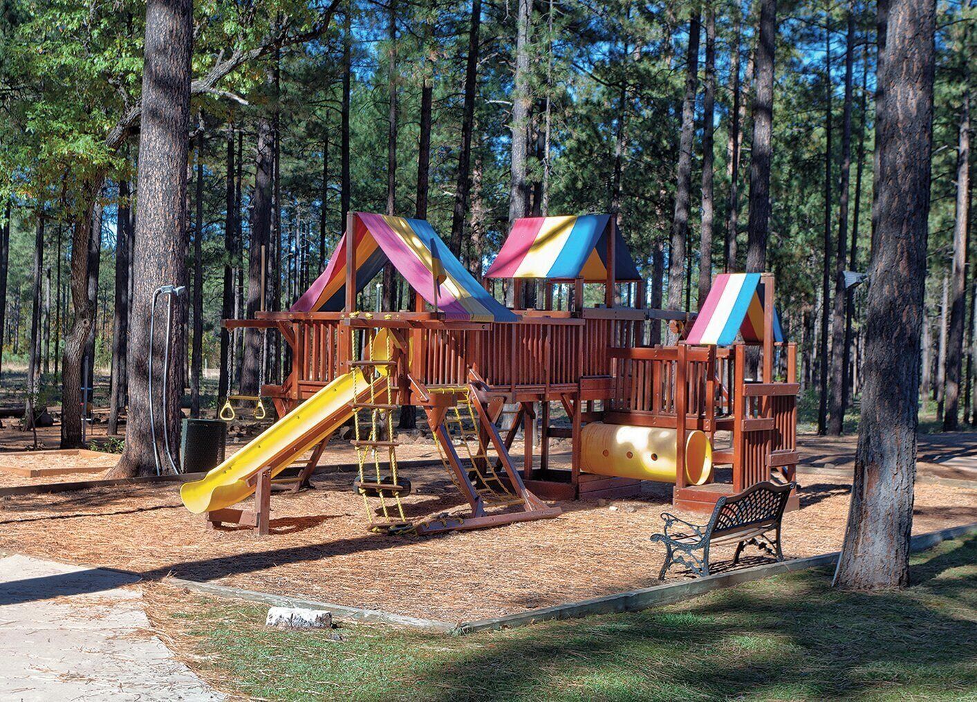 A playground with a slide, climbing structures, and a bench.