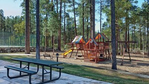 A playground with a slide and climbing structures, surrounded by tall trees. - WorldMark Pinetop (Pinetop)