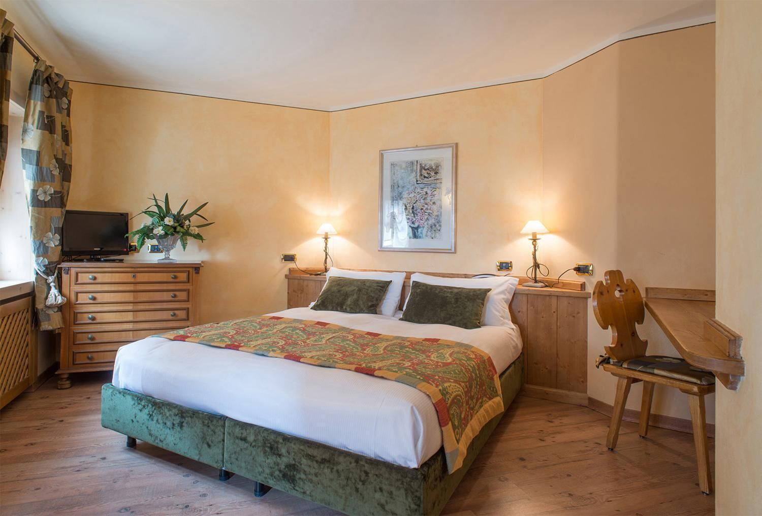 Ein Schlafzimmer mit einem Bett, einem Schminktisch, einem Fernseher und einer Lampe.