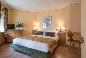 A bedroom with a bed, a dresser, a television, and a lamp. - Hotel Da Compagnoni (Valtournenche)
