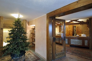 A wooden interior with a Christmas tree, a reception desk, and a patterned rug. - Hotel Da Compagnoni (Valtournenche)
