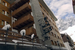 A building with wooden balconies and a stone facade, featuring a mountain backdrop. - Hotel Da Compagnoni (Valtournenche)