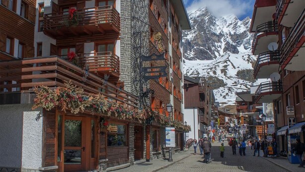 A traditional European town with stone buildings, wooden balconies, and a cobblestone street. - Hotel Da Compagnoni (Valtournenche)