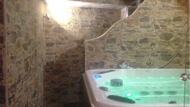 A stone-walled bathroom with a bathtub and a light fixture. - Hotel Lo Stambecco (Valtournenche)