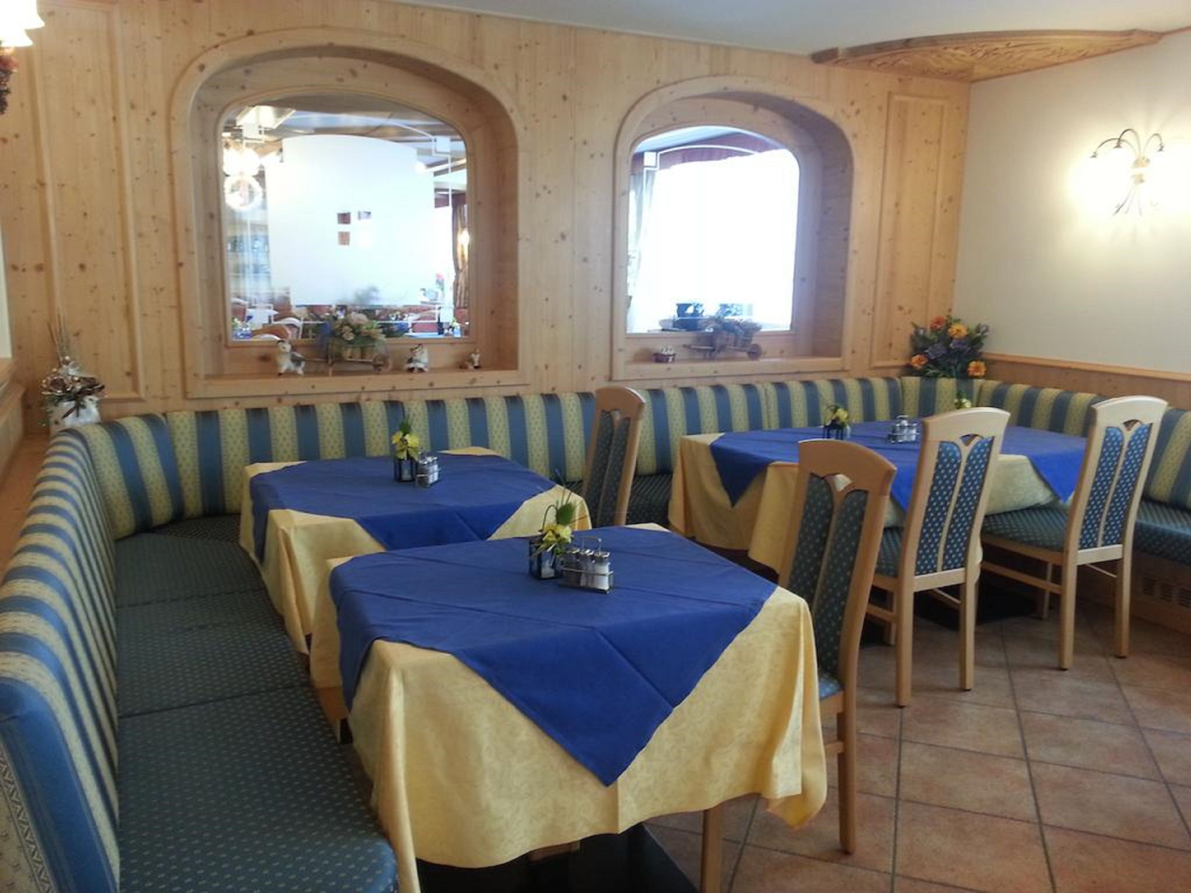 A restaurant with booths and tables, wooden walls, and a window view.